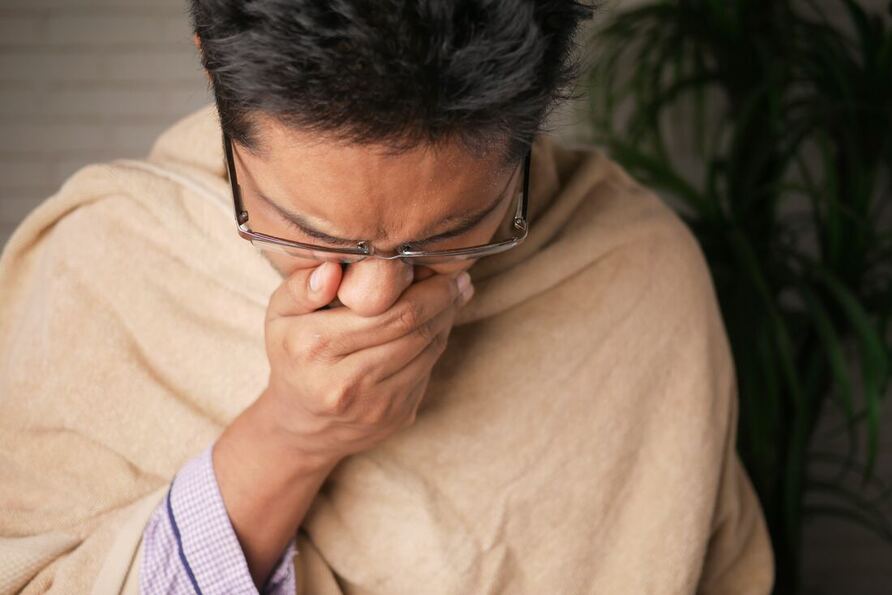 A Selinsgrove man wearing eyeglasses is wrapped in a tan towel and covers his nose while sneezing from allergies.
