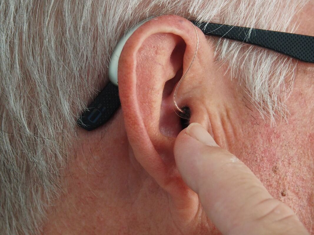 Sunbury man with eyeglass temples and temple tips on his ear wears a silver behind-the-ear hearing aid with a dome receiver.