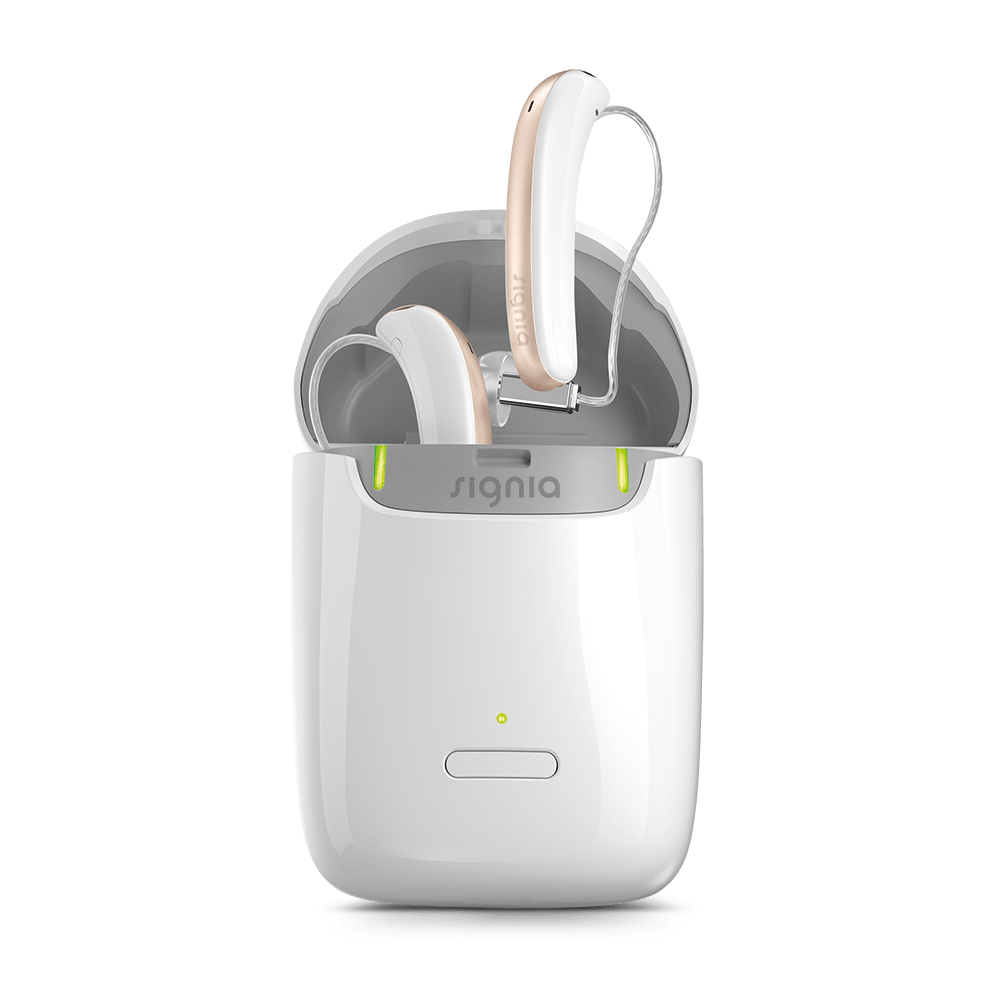 A pair of gold and white Signia Styletto X hearing aids in a white charger is placed in an upright position.