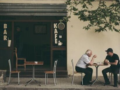 men-in-elizabethville-sit-and-chat-outside-of-a-bar-cafe-wearing-hearing-aids